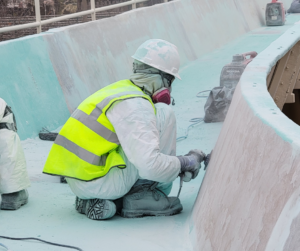worker grinding surface of a log flume ride - log flume restoration - on site service